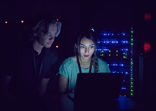 Technicians using laptop in server room