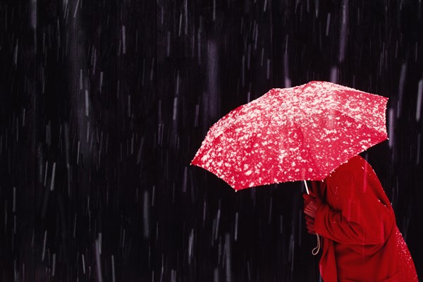 Woman walking in snowstorm with red umbrella
