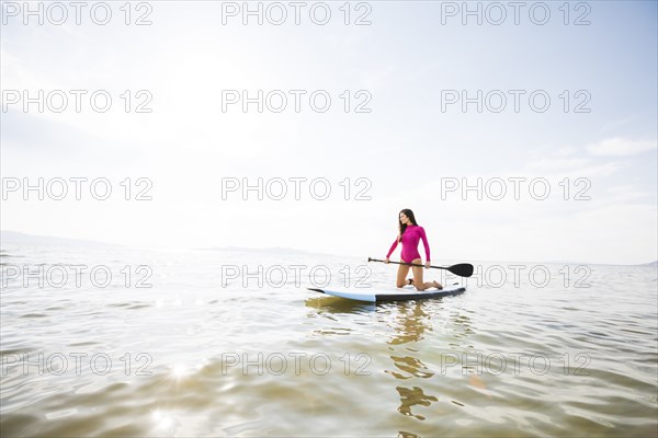 Woman kneeling on paddleboar in lake