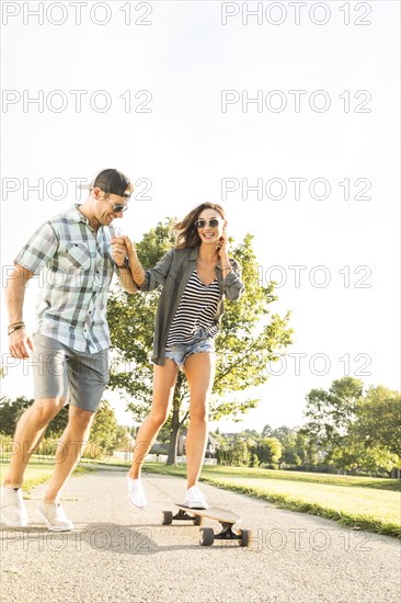 Man holding woman riding longboard