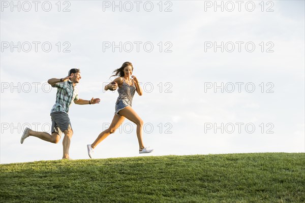 Woman and man running on grassy hill in park
