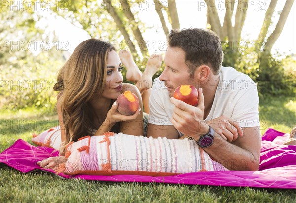 Couple eating peaches during picnic in park