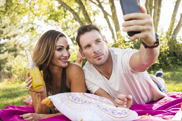 Man taking picture with smart phone at picnic in park