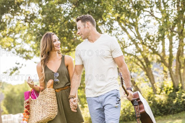 Woman and man holding hands and going for picnic in park