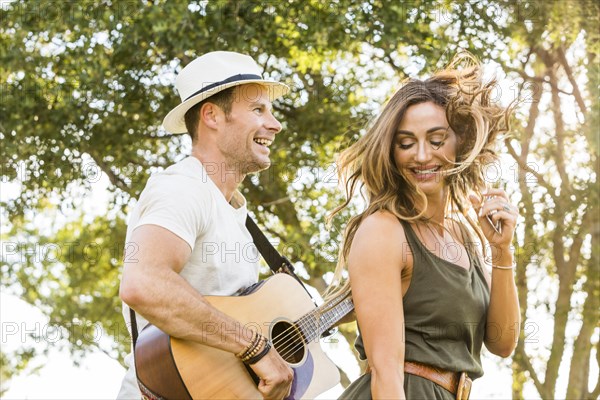 Happy woman and man having fun in park at summer