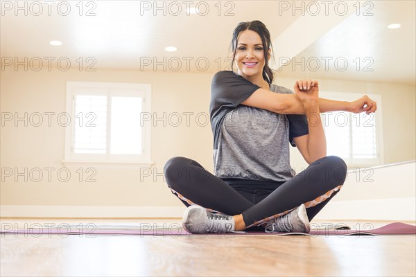 Smiling woman sitting on floor and stretching arm