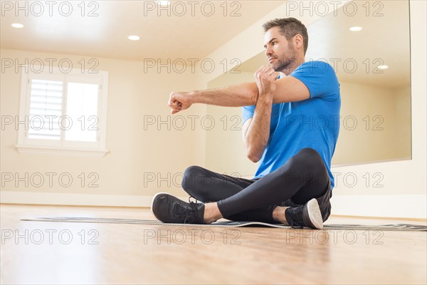 Man sitting on floor and stretching arm