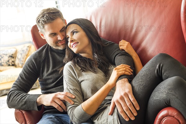 Man embracing woman sitting on armchair