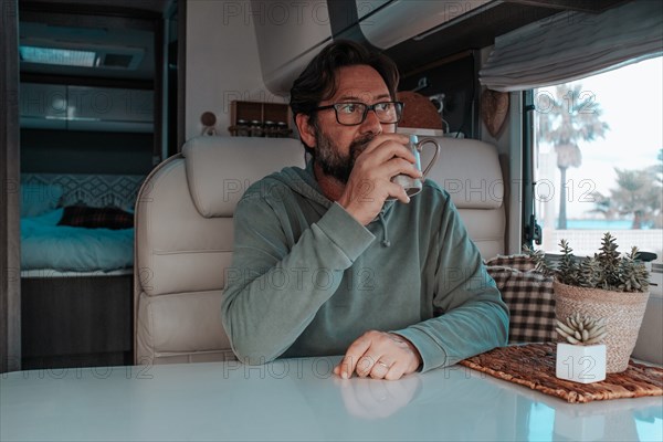 Man sitting in mobile home and drinking tea