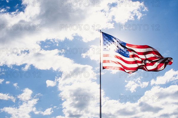 American flag blowing on wind against sky on sunny day