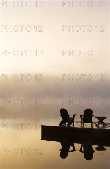 Silhouettes of adirondack chairs on pier