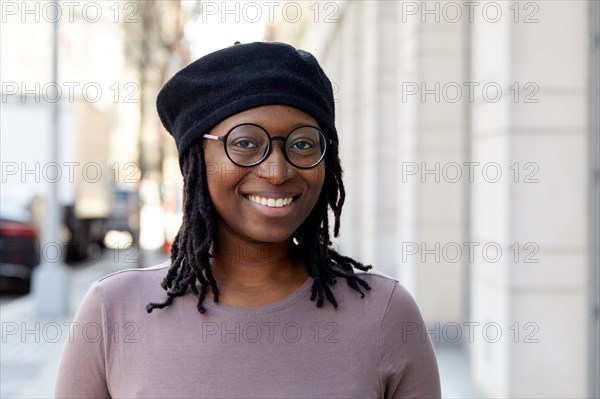 Portrait of smiling woman wearing eyeglasses and beret in city