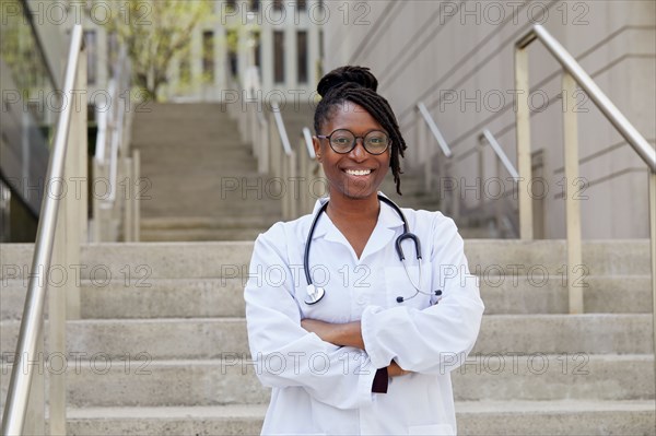 Portrait of smiling female doctor on steps in city
