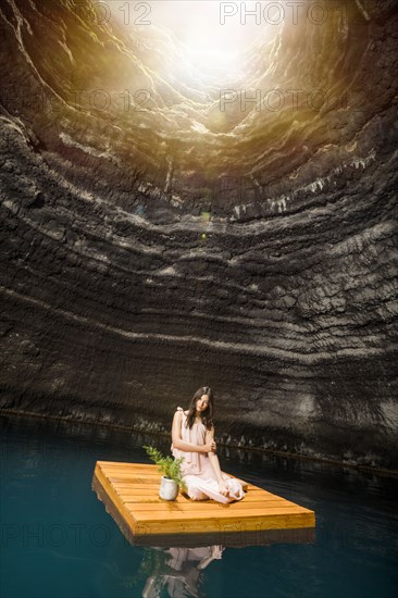 Portrait of woman sitting on floating dock near rocky coast