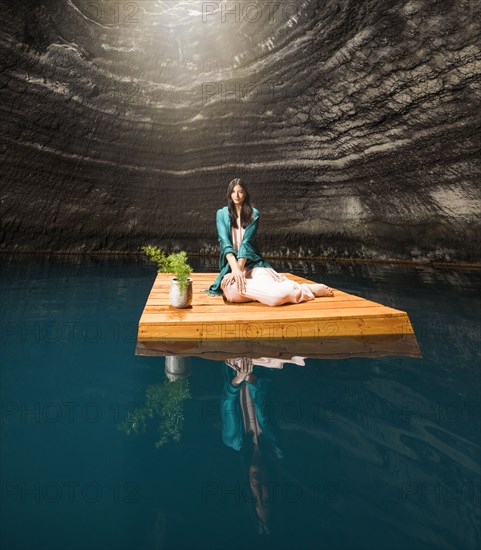 Portrait of woman sitting on floating dock near rocky coast