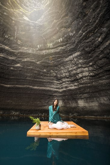 Portrait of woman sitting on floating dock near rocky coast