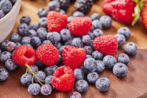 Studio shot of fresh blueberries and raspberries on wooden surface