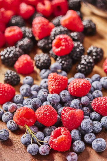 Studio shot of fresh blueberries and raspberries on wooden surface