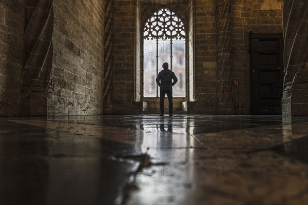 Rear view of man looking through window in old empty church