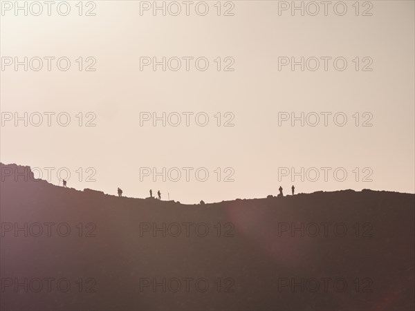 Silhouettes of hikers on mountain ridge at sunset