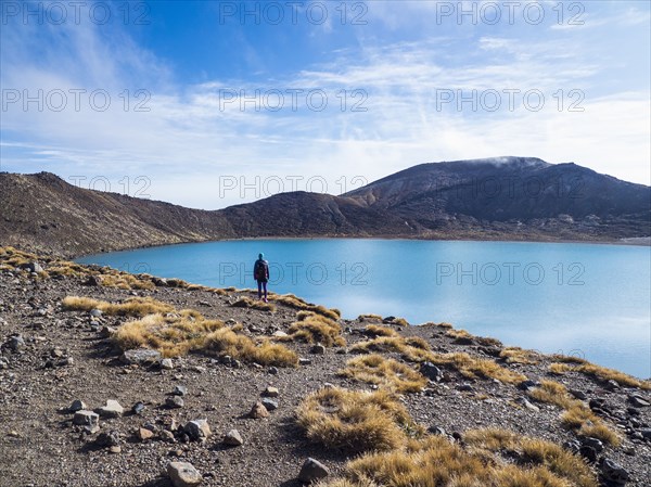 Hiker standing by lake in Volcanic landscape