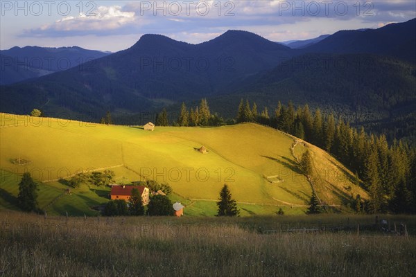 Houses in rural landscape in Carpathian Mountains at sunset