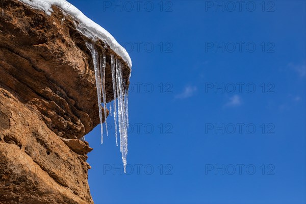 Icicles hanging from rock against blue sky
