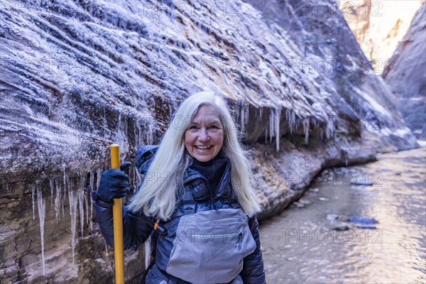 Senior woman crossing river while hiking in mountains