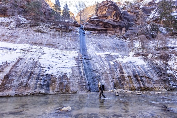 Senior woman crossing river while hiking in mountains