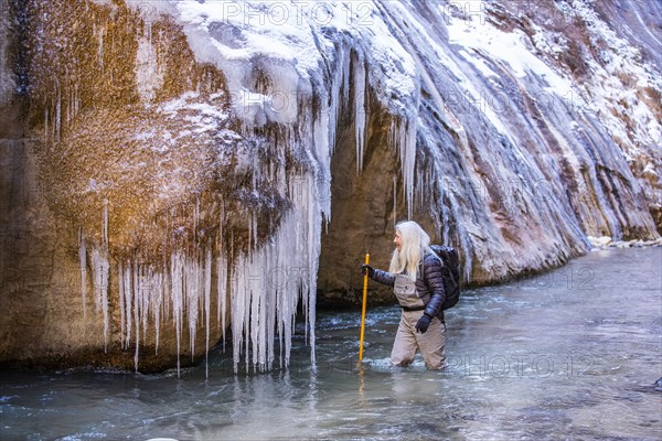 Senior woman crossing river while hiking in mountains