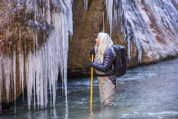 Senior woman looking at icicles while hiking in mountains