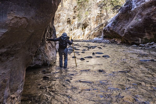 Senior woman crossing river while hiking in mountains