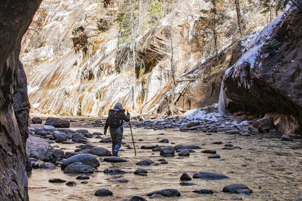 Senior woman crossing stream while hiking in mountains