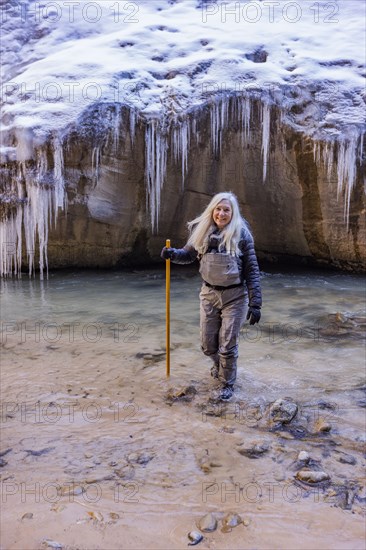 Senior woman crossing river while hiking in mountains