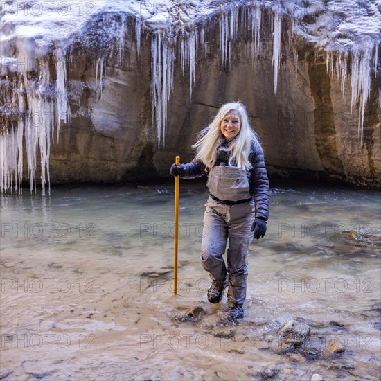 Senior woman crossing river while hiking in mountains