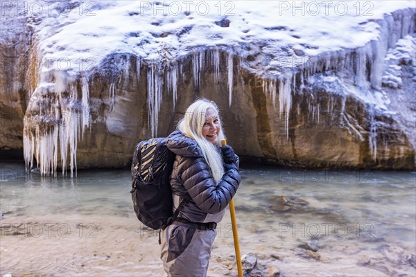 Senior woman crossing river while hiking in mountains