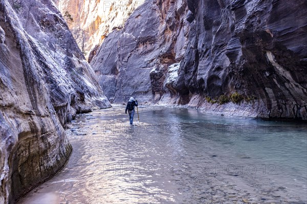 Senior woman crossing river while hiking in mountains