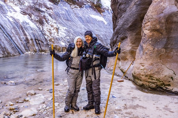 Senior couple crossing river while hiking in mountains