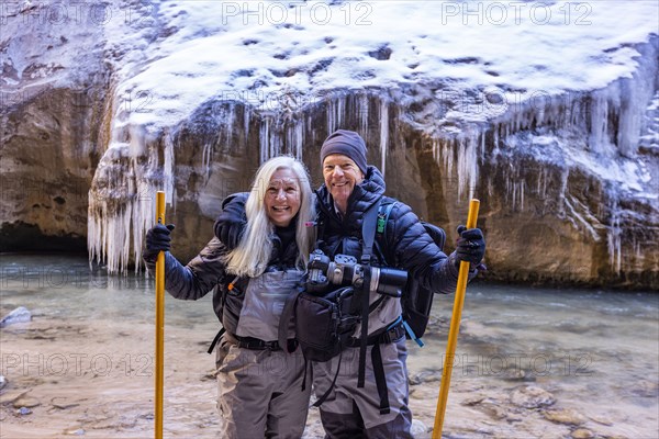 Senior couple crossing river while hiking in mountains