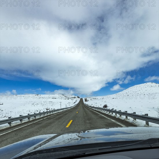 Highway through snow-covered landscape as seen from car