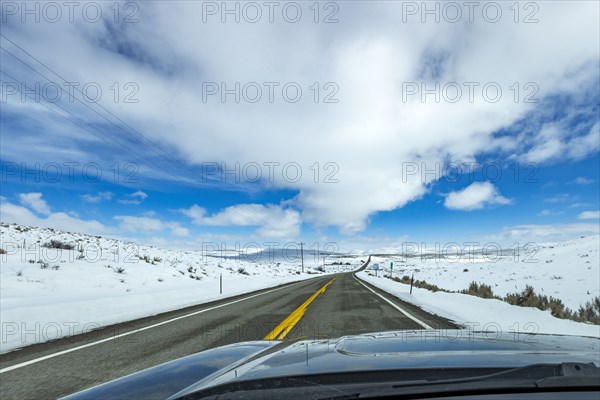 Highway through snow-covered landscape as seen from car