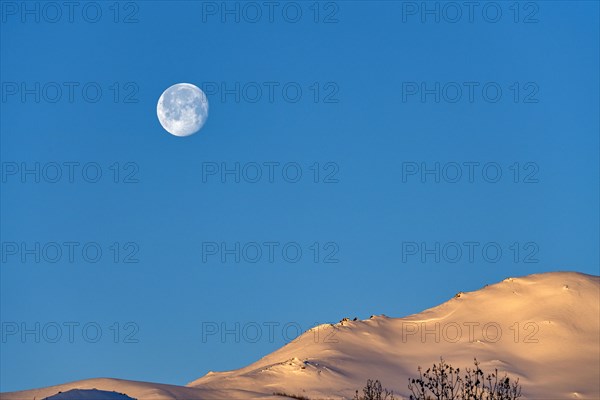 Full moon over snow-covered hills