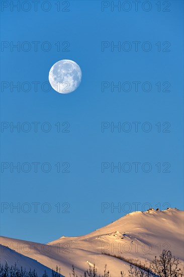 Full moon over snow-covered hills