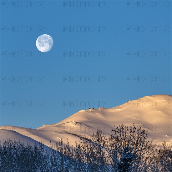 Full moon over snow-covered hills