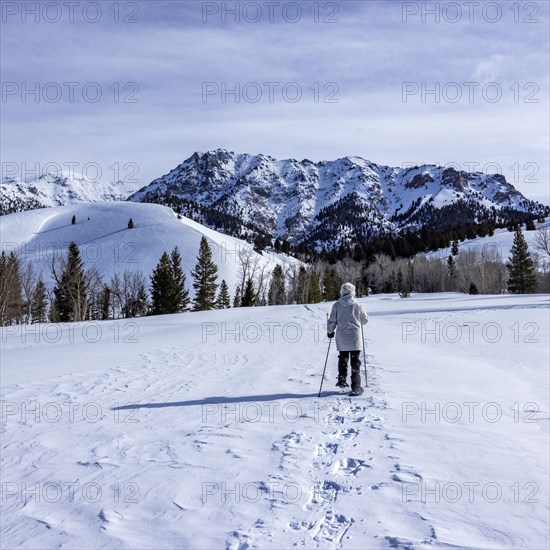 Senior woman wearing snowshoes hiking in mountains