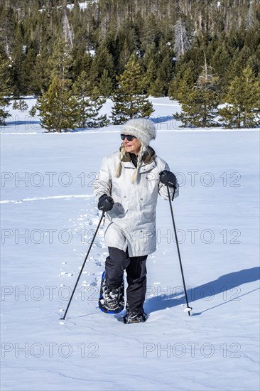 Senior woman wearing snowshoes hiking in mountains
