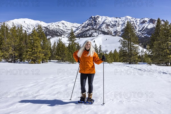 Smiling woman snowshoeing in mountains