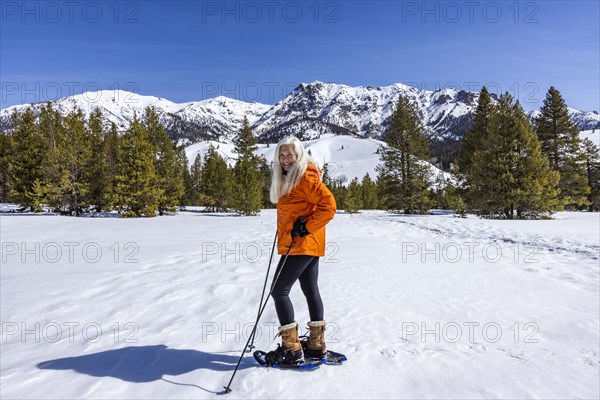 Smiling woman snowshoeing in mountains