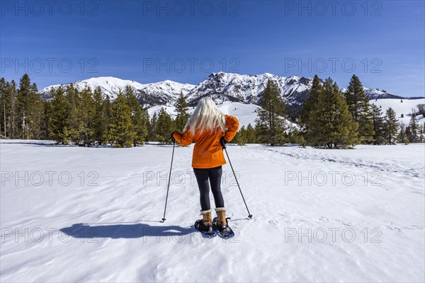 Back view of woman snowshoeing in mountains