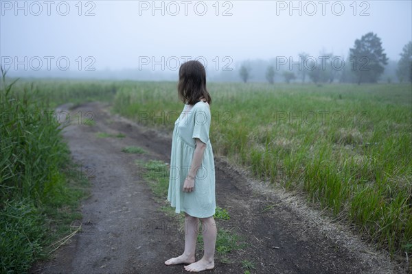 Woman standing on dirt road and looking away